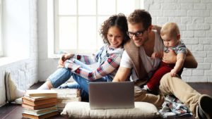 A family sitting on the floor looking at a laptop