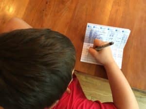 A boy writing on paper with a pen.