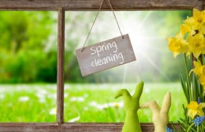 A sign hanging in front of a window that says spring cleaning.