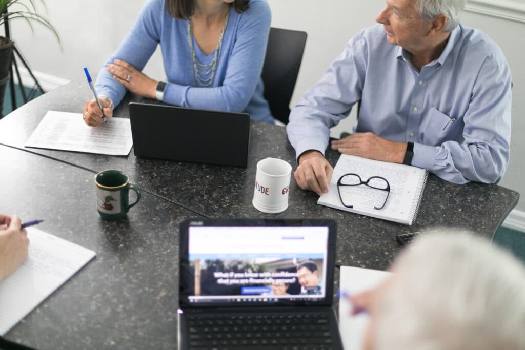 A group of people sitting around a table with laptops.